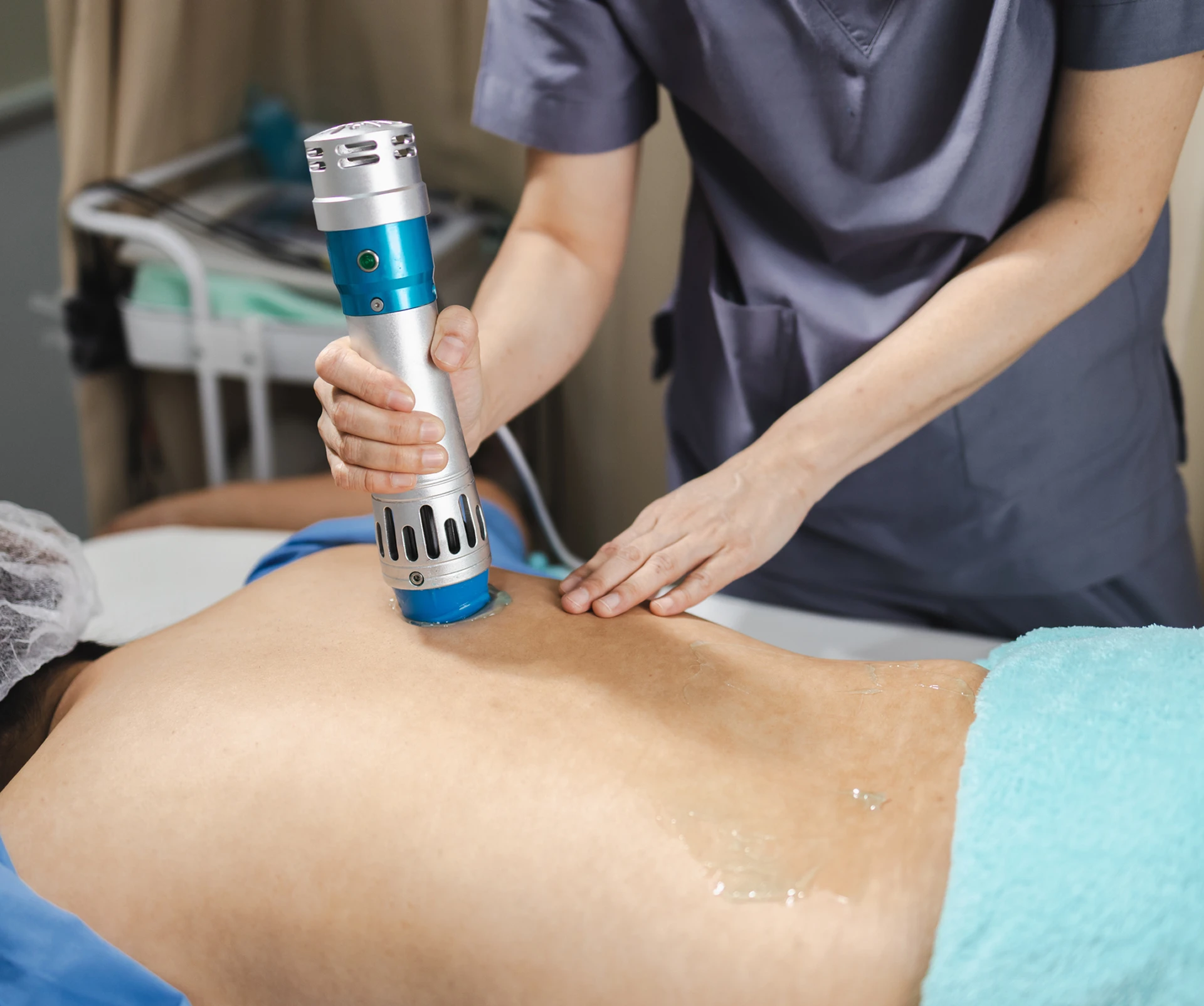 Therapist using device on patient's back.