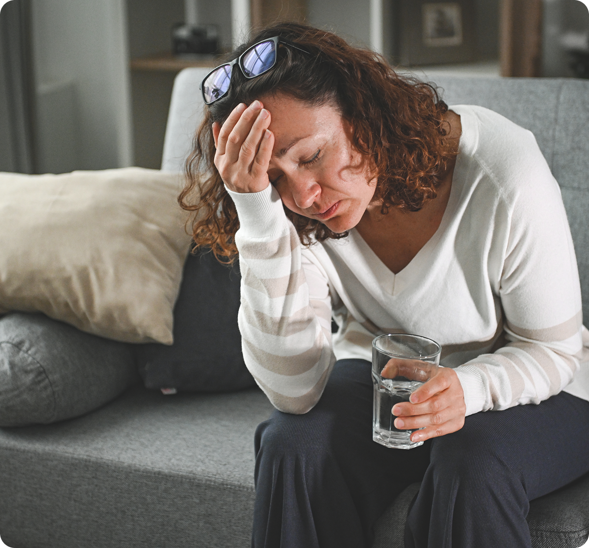 Tired woman sitting on gray sofa